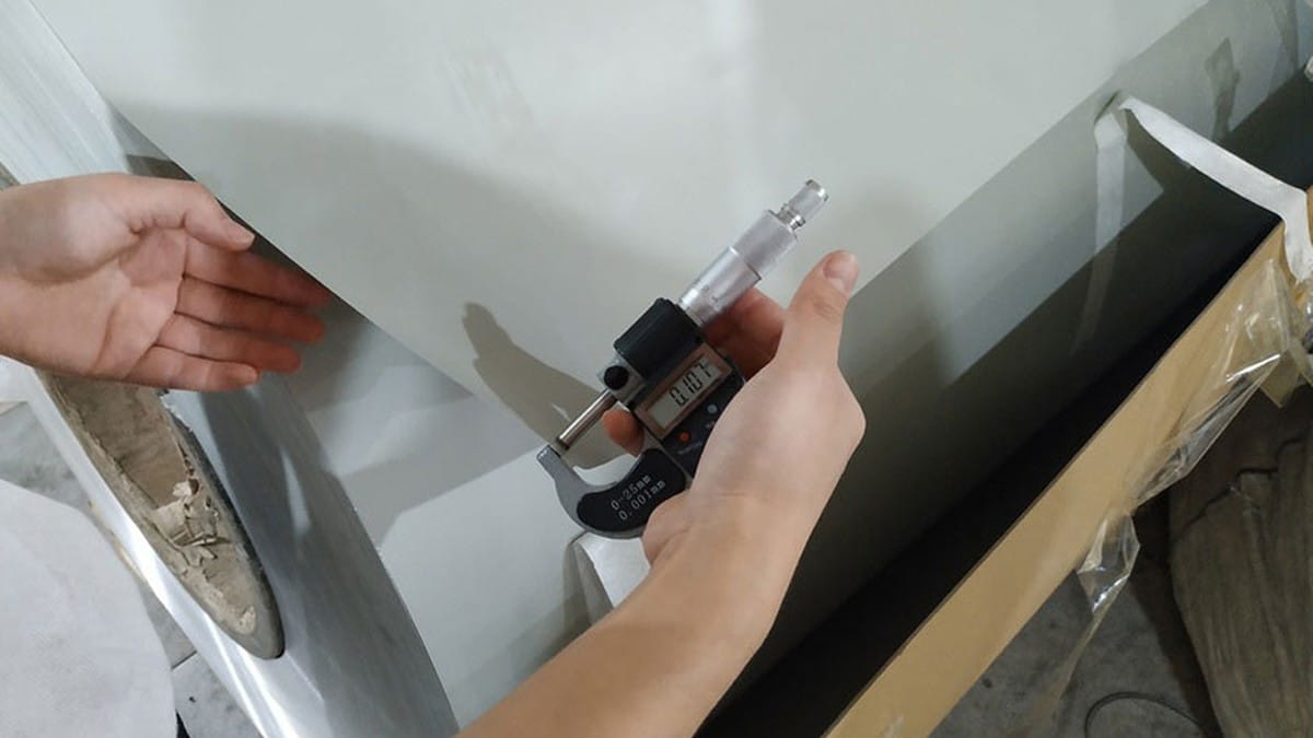 Inspector checking aluminum skin thickness on an ACP sample