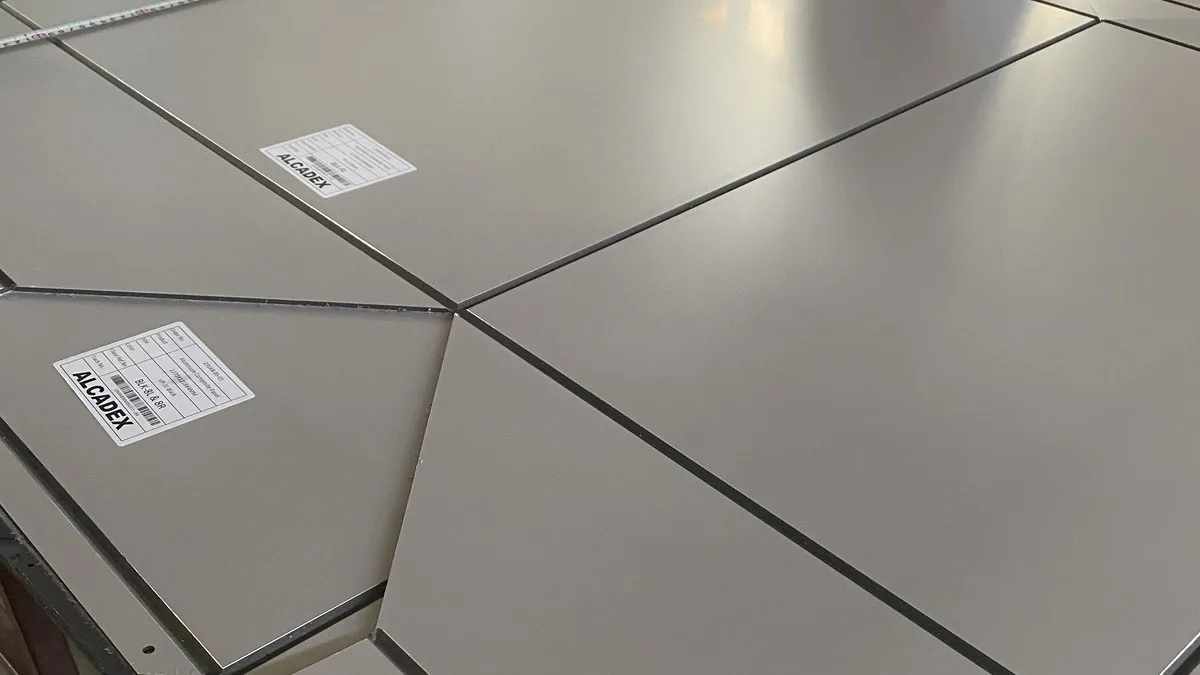 Massive Alcadex-Verbundplatten mit Kennzeichnungsetiketten sind auf einem Fertigungstisch angeordnet.